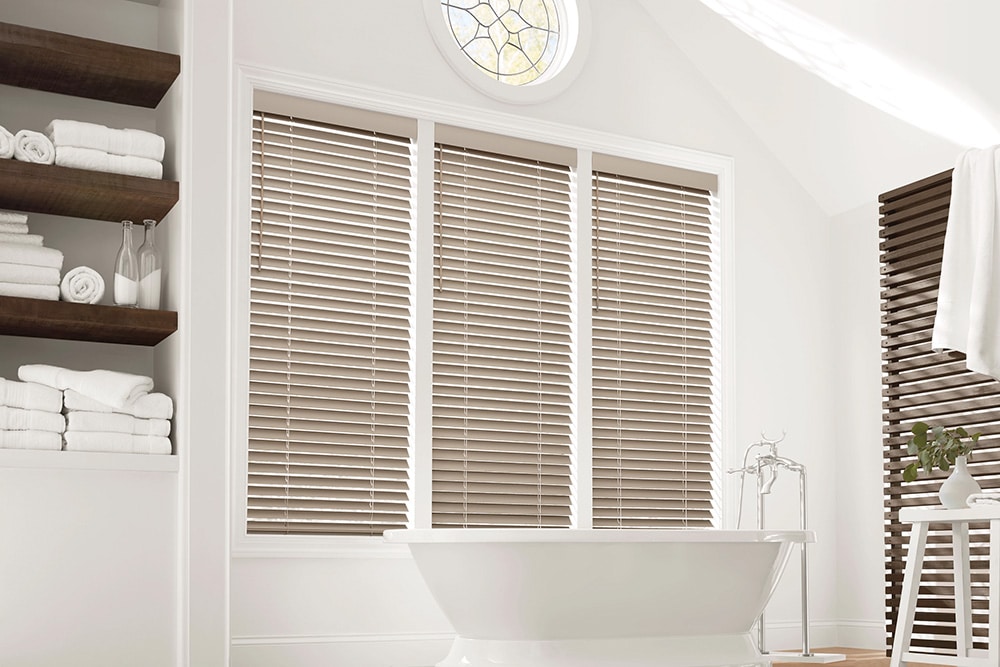 Faux Wood blinds filtering in light to a sleek modern looking bathroom.